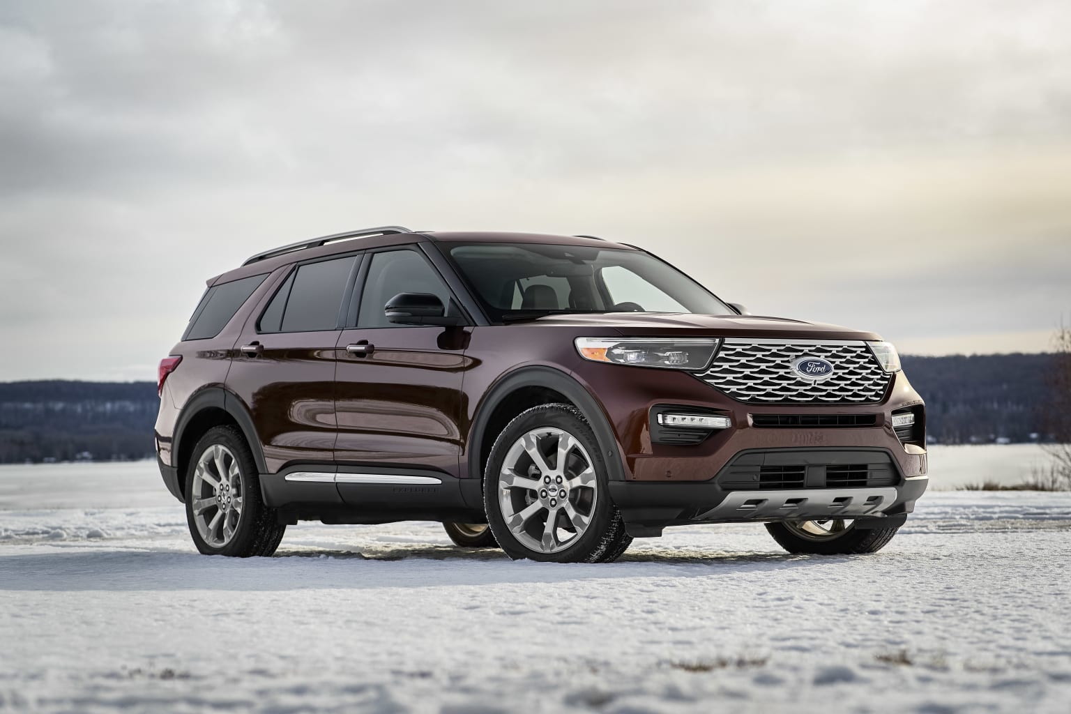 a brown ford explorer is parked on a snowy surface in the snow, with a cloudy sky in the background