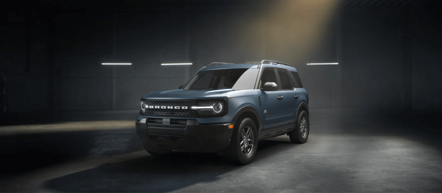 A blue SUV is parked in a dimly lit garage with overhead lights.
