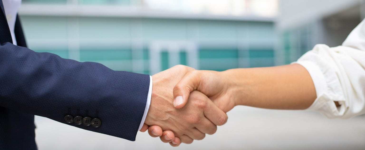 a close up of a person shaking another person's hand with a building in the background behind them