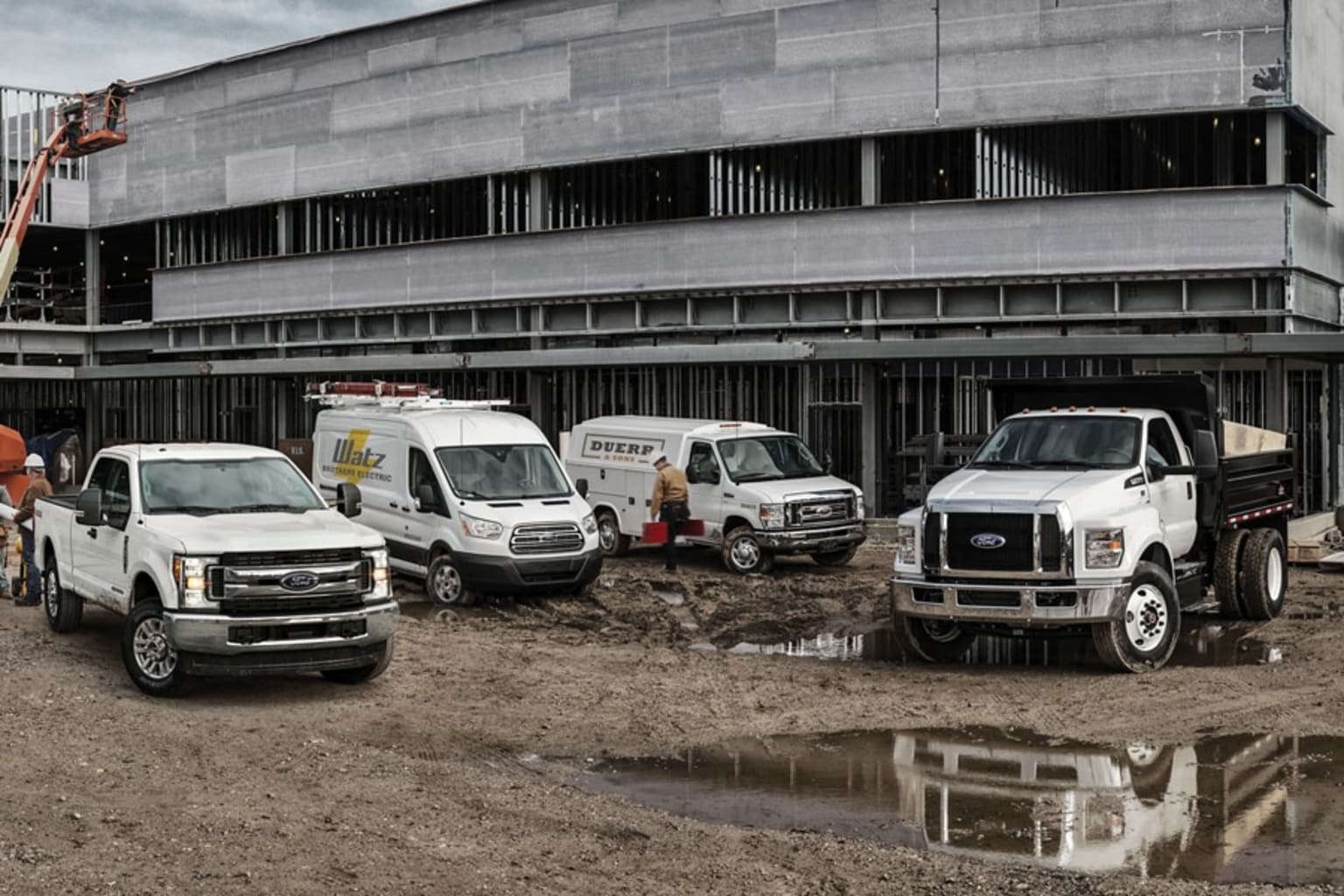 a group of trucks parked next to each other in front of a large building with a crane on top of it