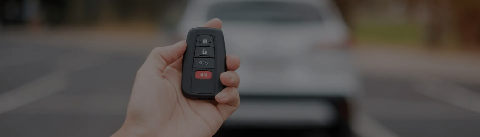 Hand holding a black remote control with various buttons.