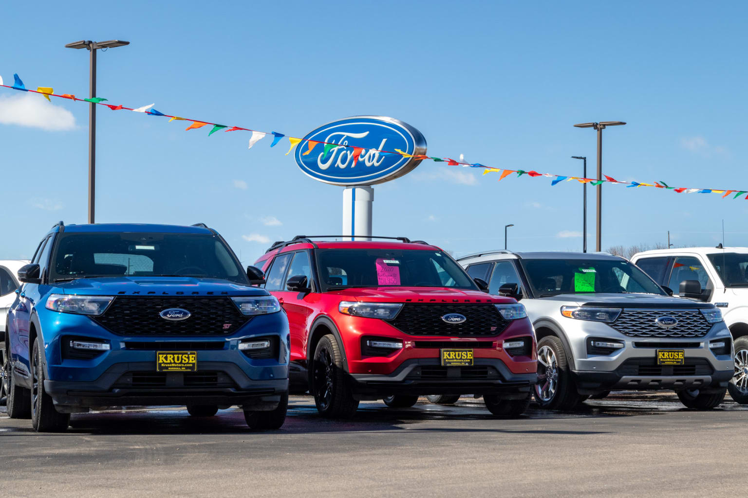 a row of ford vehicles parked in front of a ford dealership with a ford sign in the background