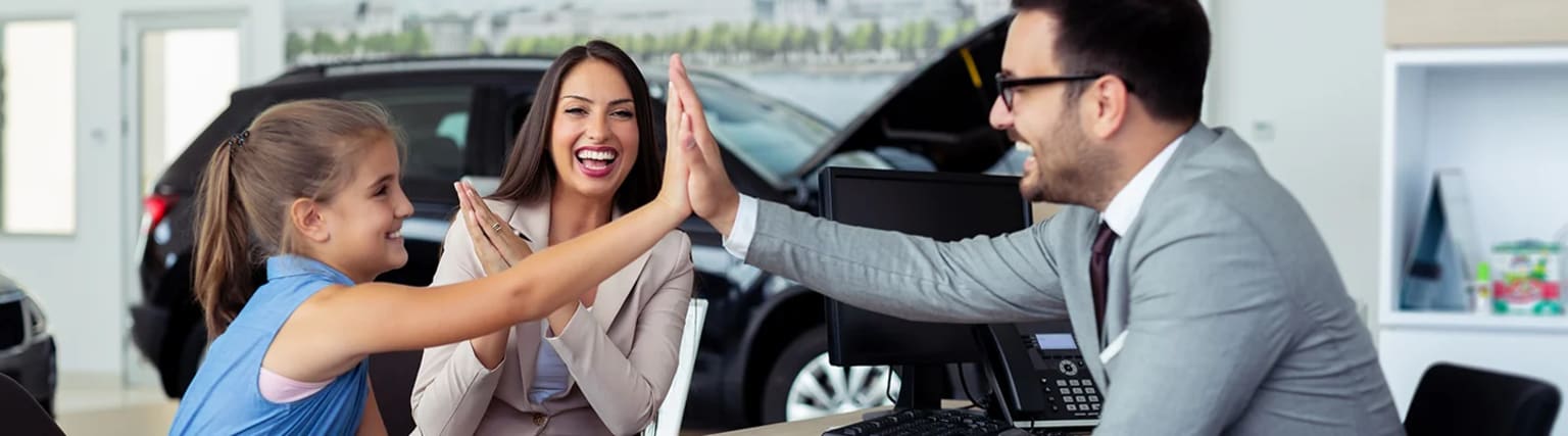 Two people high-fiving each other, with a car in the background.