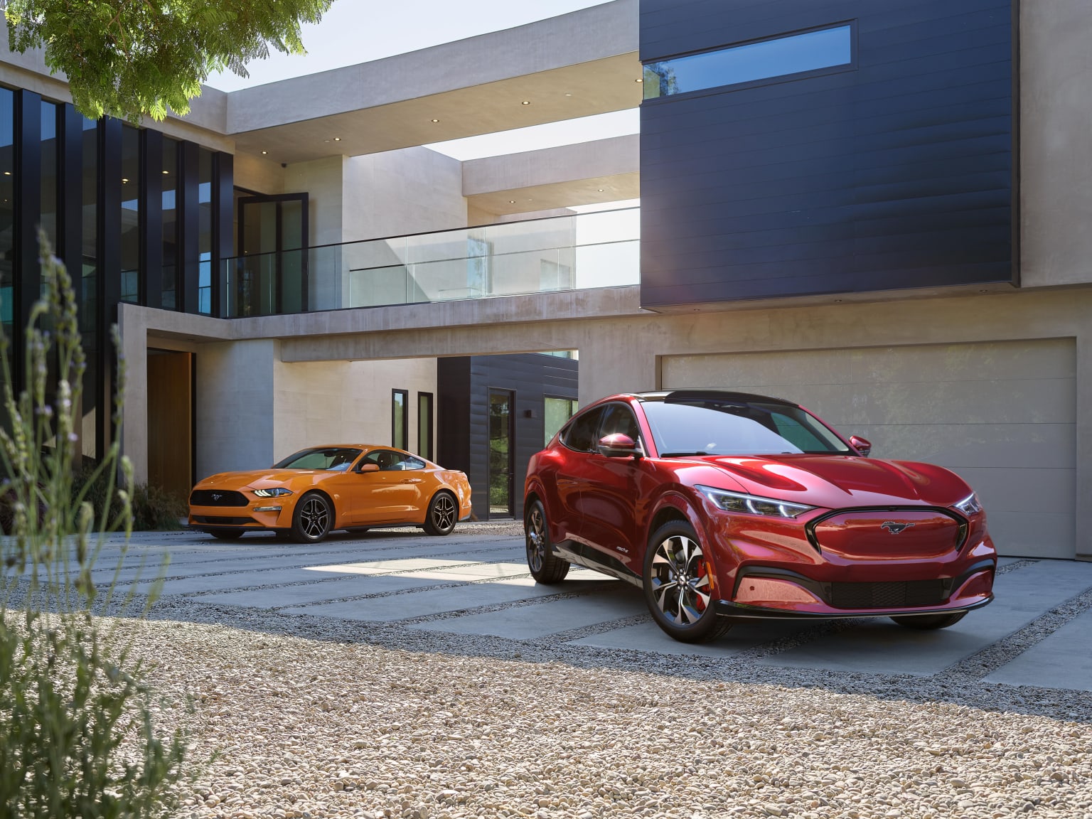 two red cars parked in front of a modern house with a balcony and balconies on the second floor