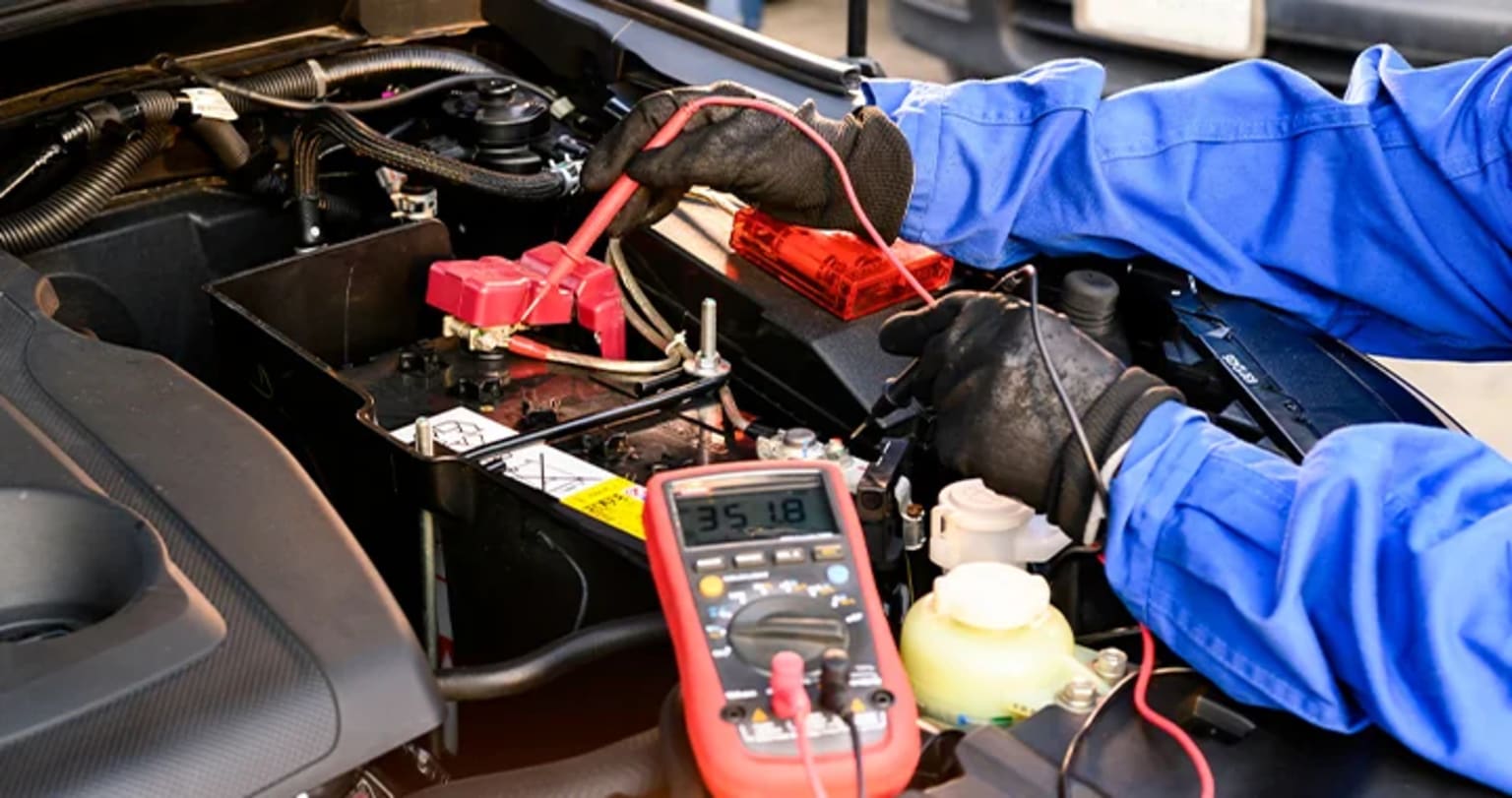 Interior of a vehicle with tools and equipment such as a multimeter and blue clothing items.