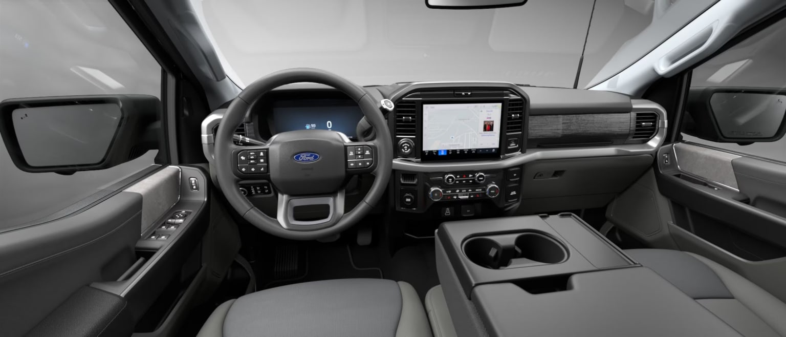 Interior of a vehicle with a steering wheel, dashboard, and various controls and displays visible.