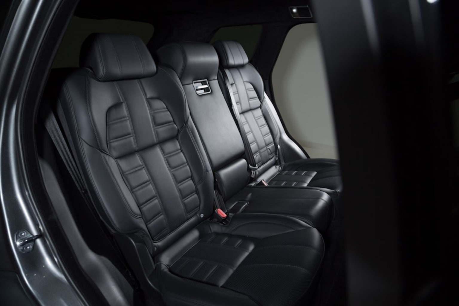 the interior of a car with black leather seats and a red button on the left side of the car