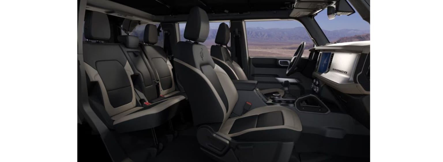 The image shows the interior of a spacious vehicle with rows of comfortable-looking seats and a view of a mountainous landscape visible through the windows.