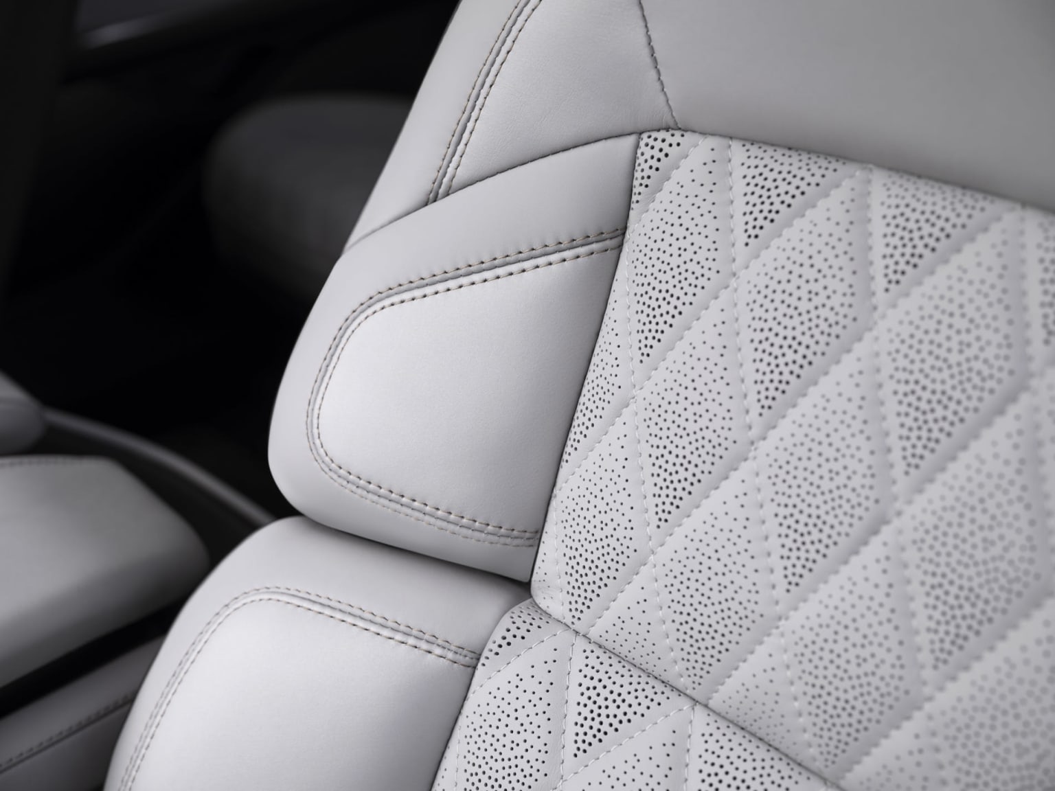 Interior of a vehicle with white leather seat upholstery featuring a textured, diamond-patterned design.