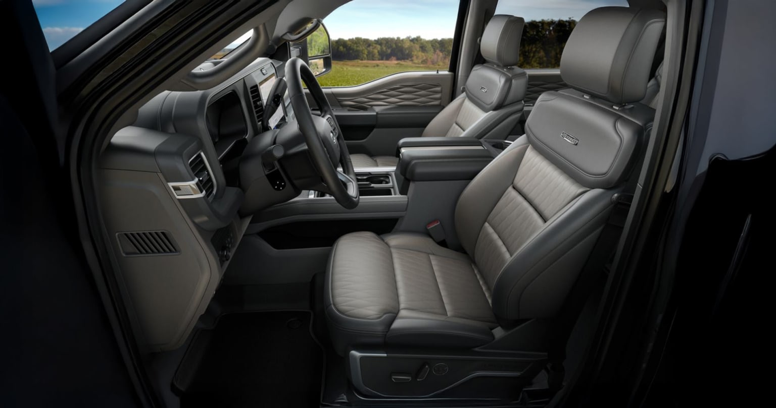 Interior view of a vehicle with leather seats and a forested background.