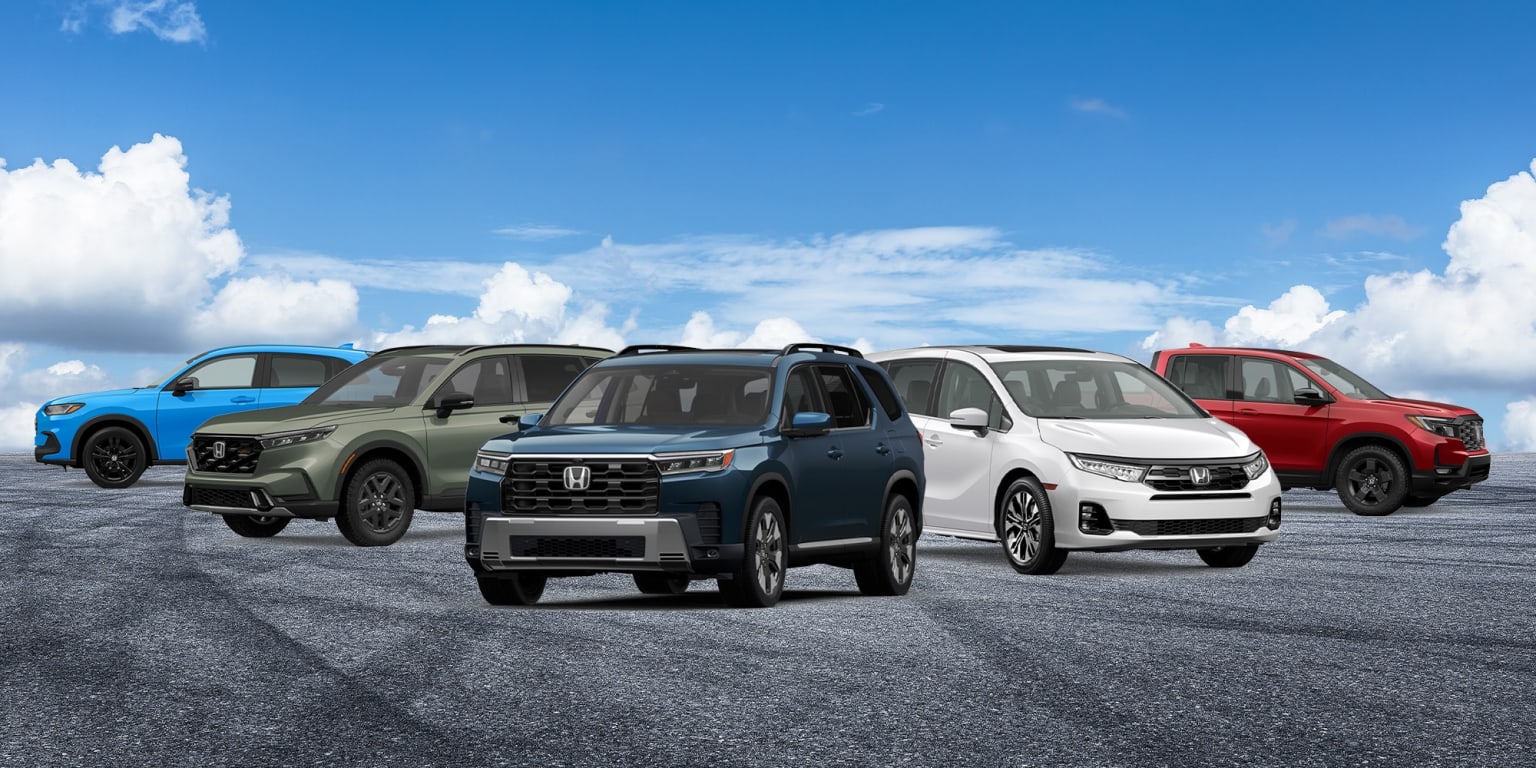 Several vehicles are parked on asphalt under a blue sky with scattered clouds.