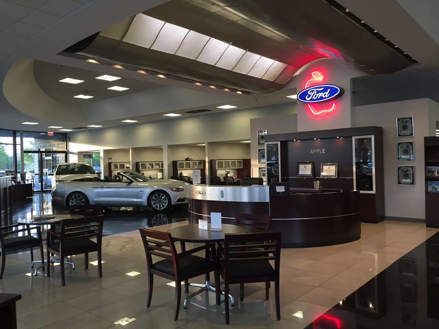 the interior of a car dealership with a car parked in the back bay of the car dealership