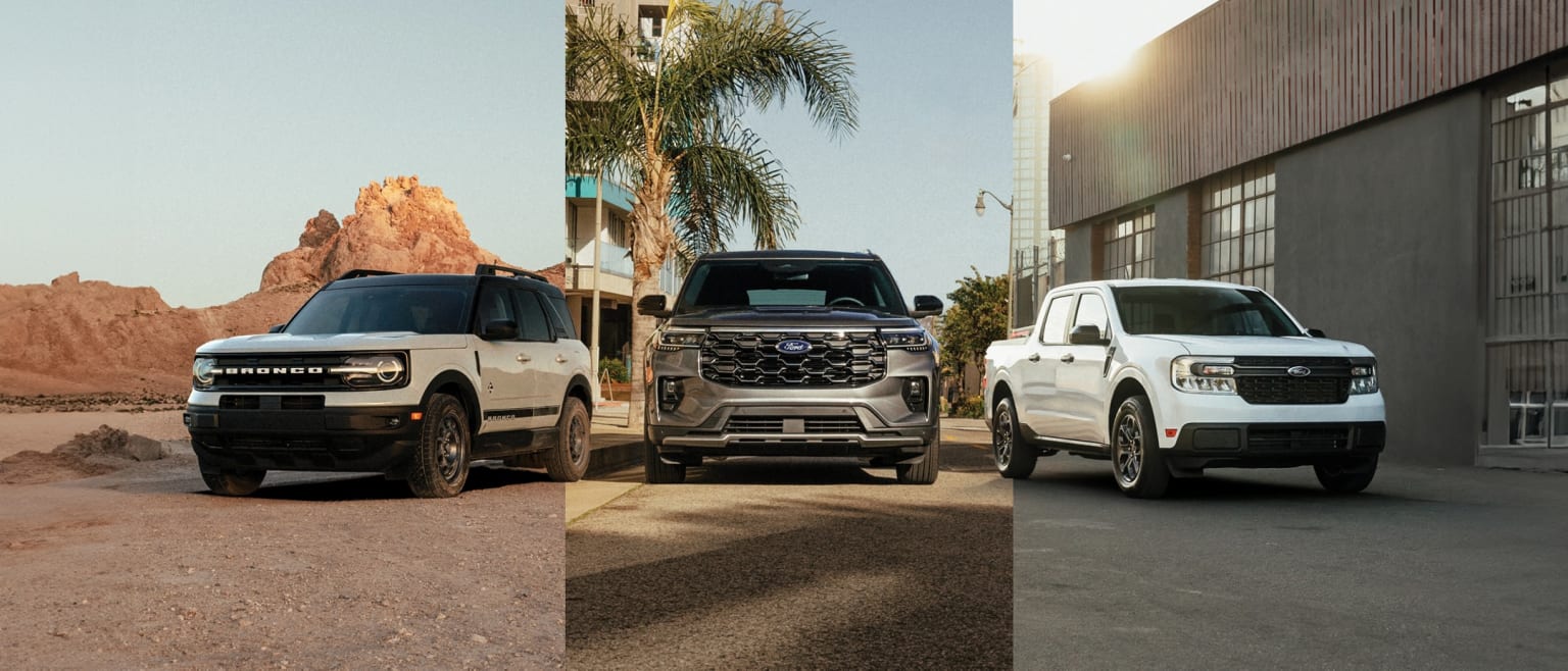 Large SUV-style vehicles parked in a desert-like setting with a rocky outcrop and palm trees in the background.