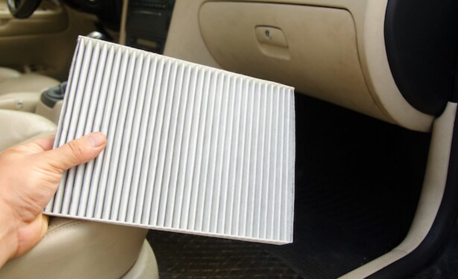 a person holding a piece of paper in their hand in front of the door of a car with the driver's side door open