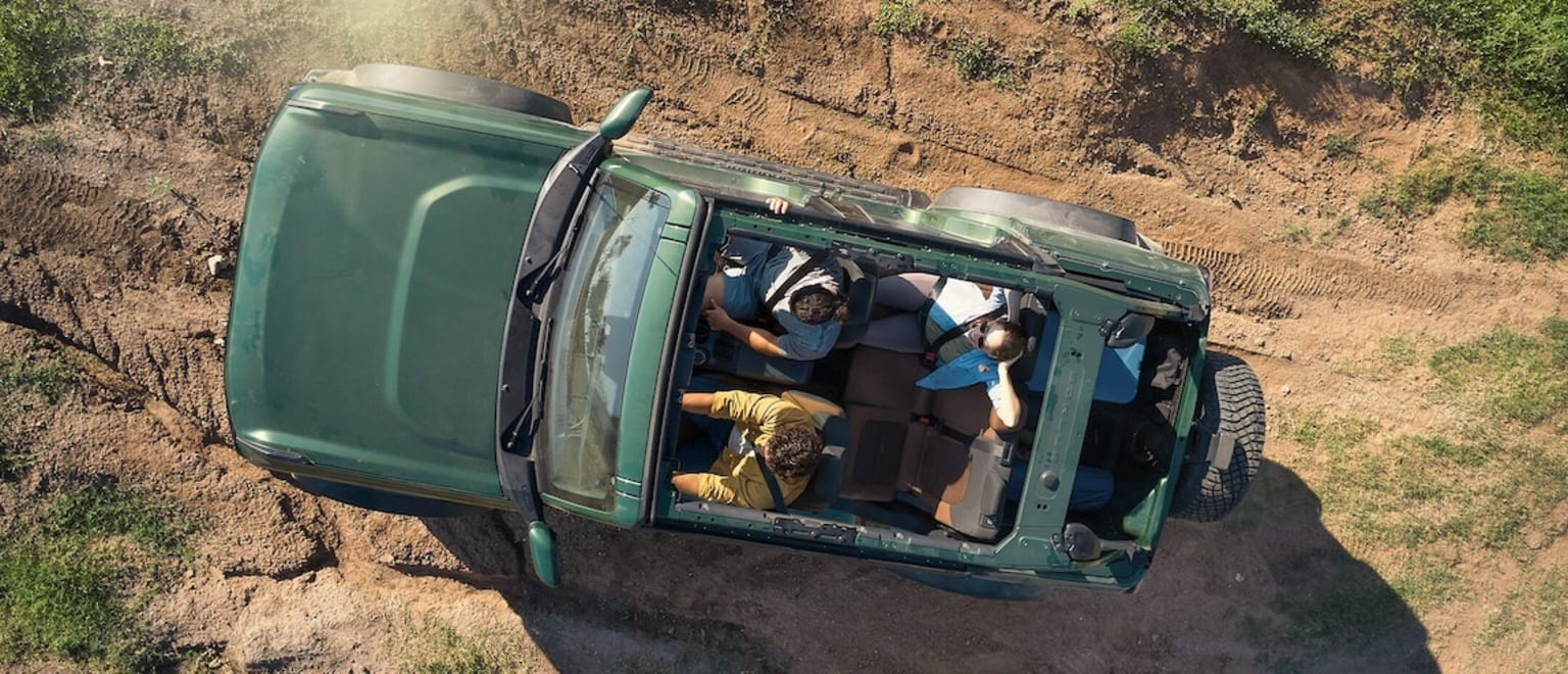 An off-road vehicle stuck in muddy terrain with people inside trying to free it.