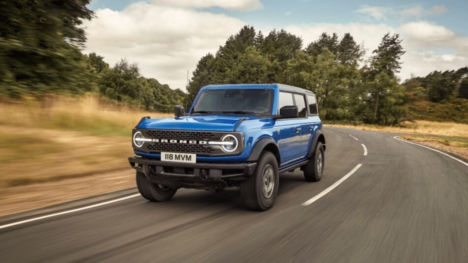 A blue Ford Bronco driving on a street.