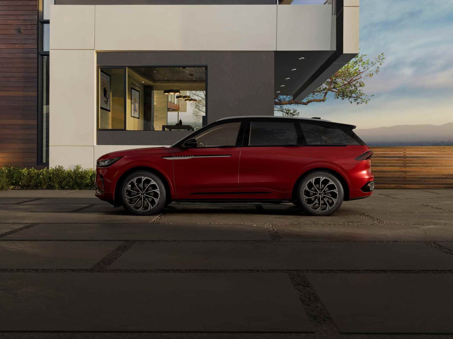 Red SUV in front of a modern building with glass facade against cloudy sky