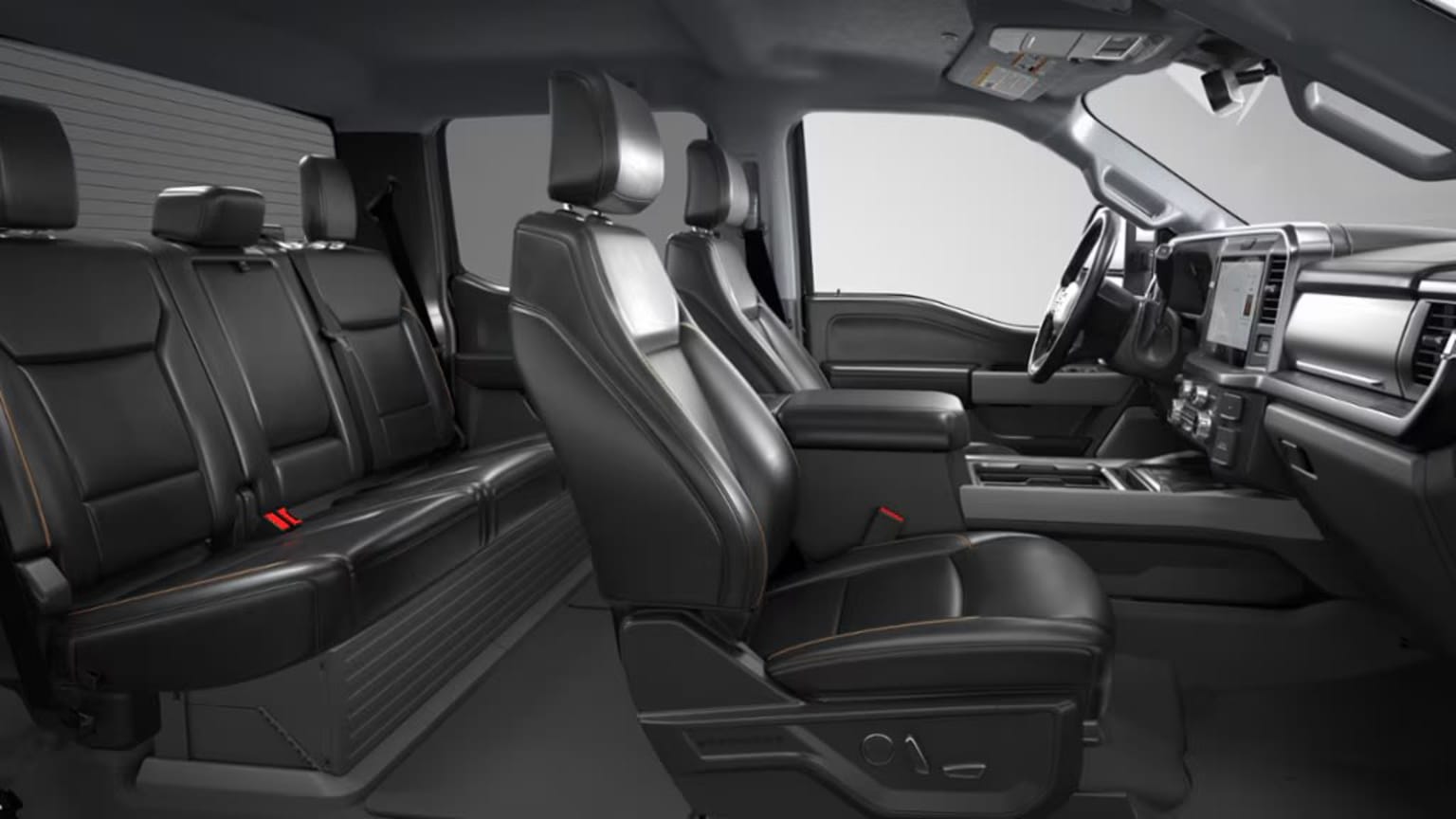 The image shows the interior of a vehicle, with rows of black leather seats and various controls and displays visible in the background.