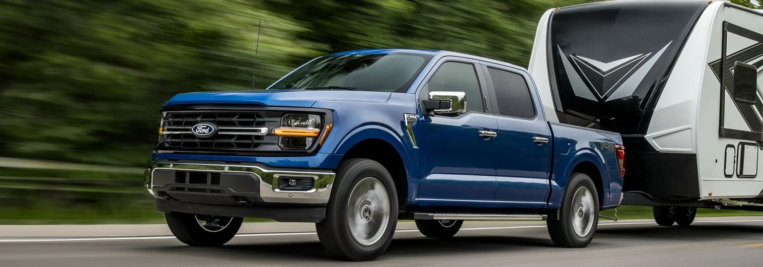 Image alt text: A blue pickup truck speeding through a lush green landscape.