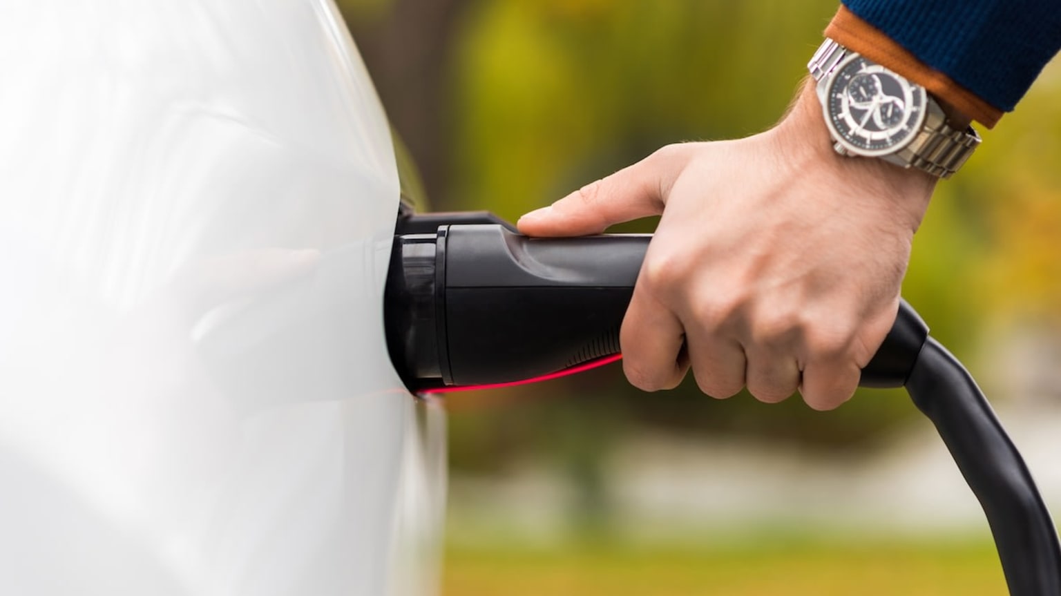 a man is holding onto the handle of a car with his hand on the handle of the car and a watch on his wrist