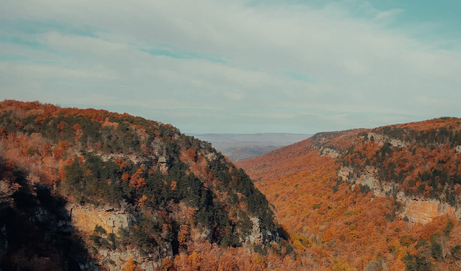 a scenic view of a mountain range with trees in the foreground and a blue sky in the background