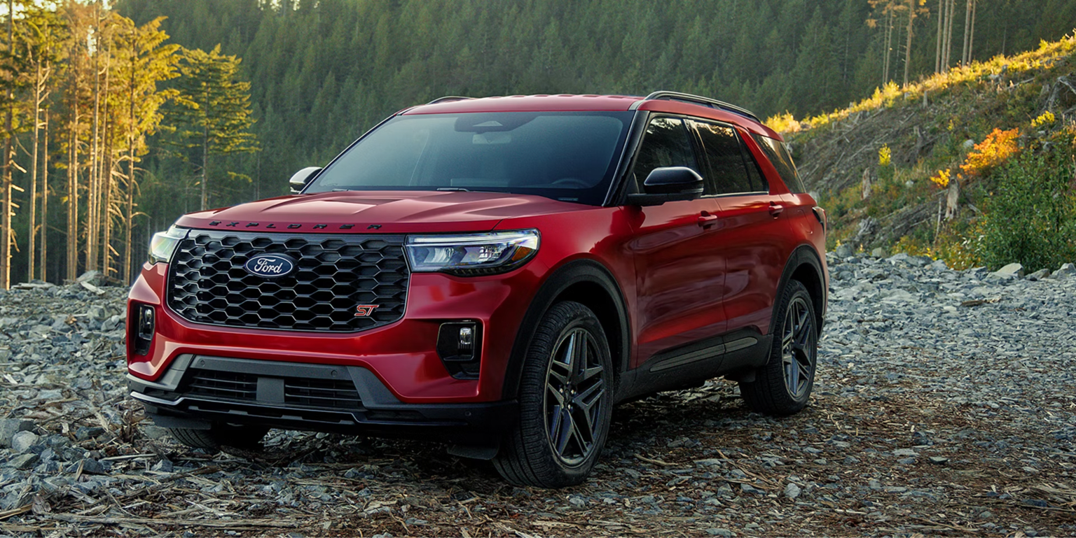 Red SUV parked on rocky terrain with forest in the background.