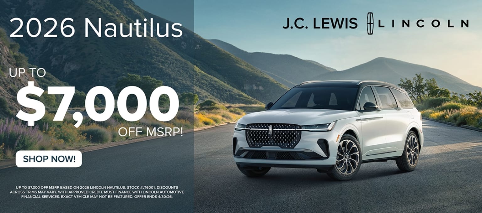 A white SUV parked in front of a scenic mountainous landscape.