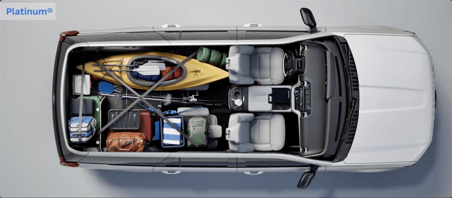 Interior of a van or cargo vehicle filled with various tools, equipment, and supplies, including a toolbox, a yellow hard hat, and other miscellaneous items.