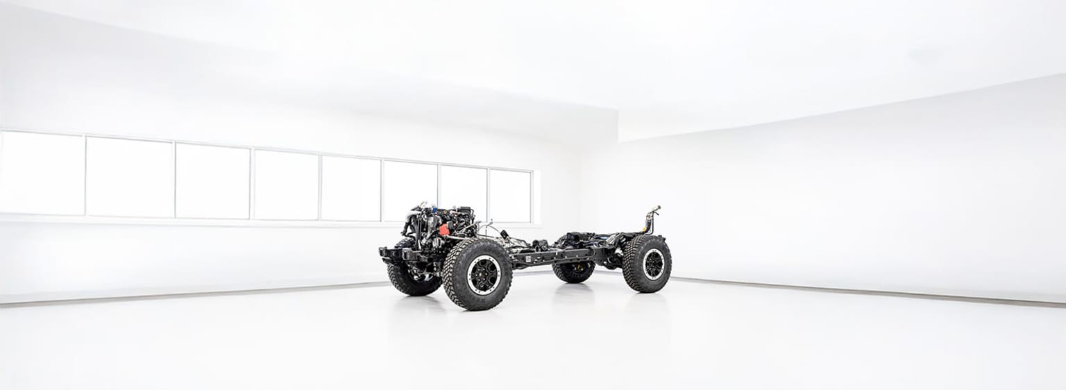 A large, black tractor in a minimalist, white-walled room.