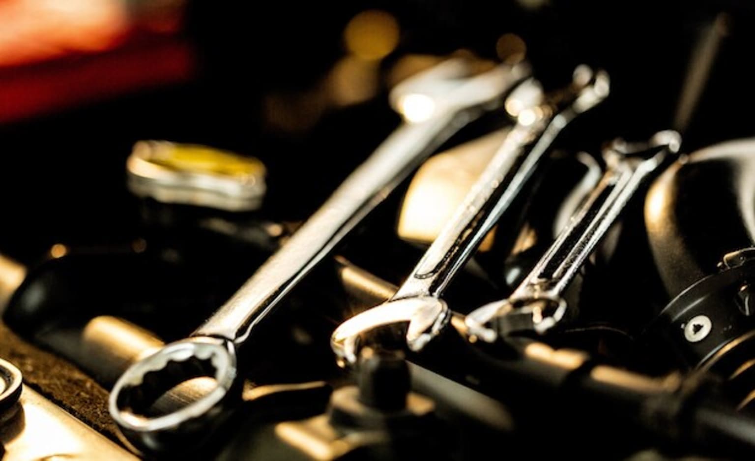 a close up of a bunch of wrenches and other tools on top of a metal table with a red light in the background