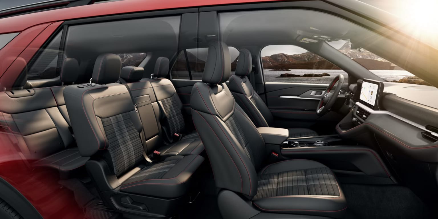Interior of a vehicle with rows of comfortable-looking seats and a scenic landscape visible through the windows.