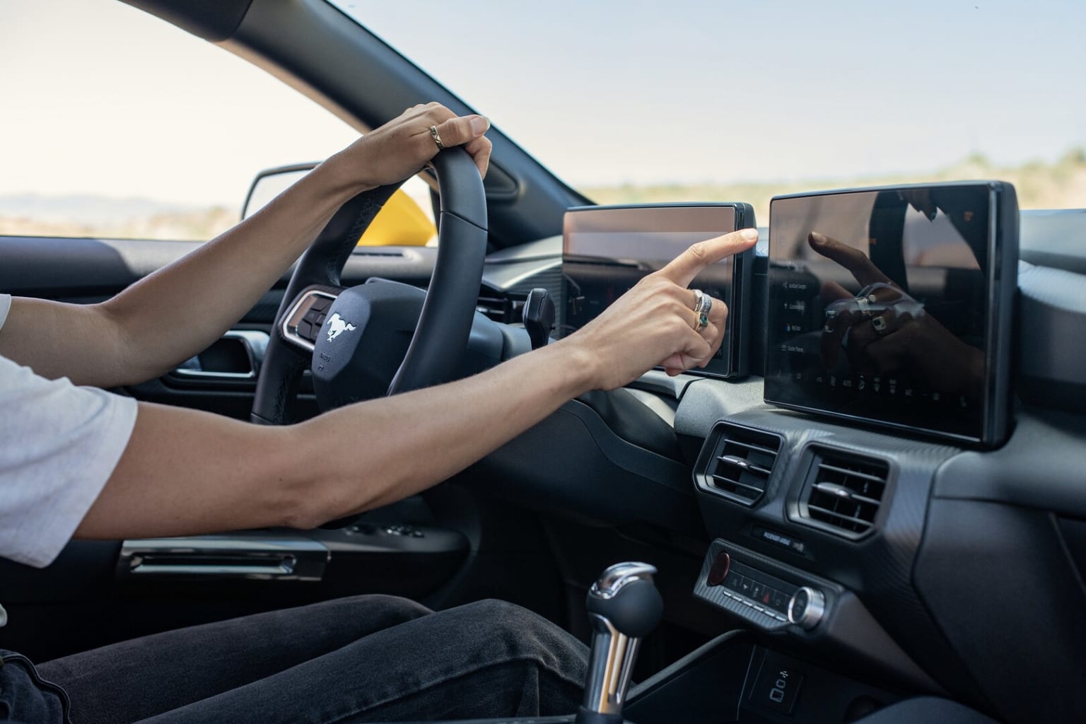 Interior of a car with hands on the steering wheel and a mobile device mounted on the dashboard.