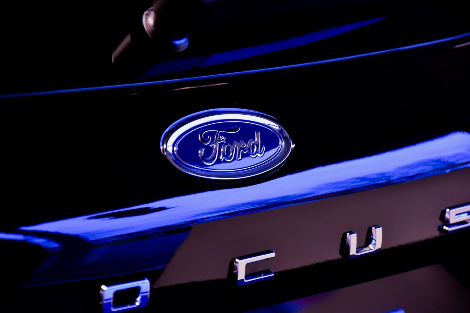 a close up of the emblem on the front of a ford vehicle in the dark with a blue light