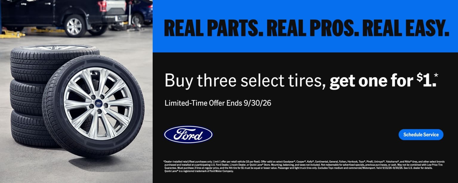 A stack of tires and a vehicle on a lift in front of a promotional background