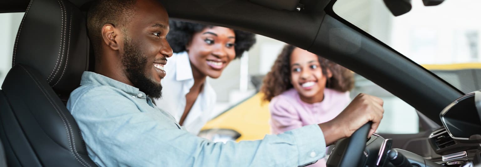 The image shows a group of three people, two women and one man, sitting together in what appears to be a vehicle. They are all smiling and seem to be engaged in a friendly conversation.