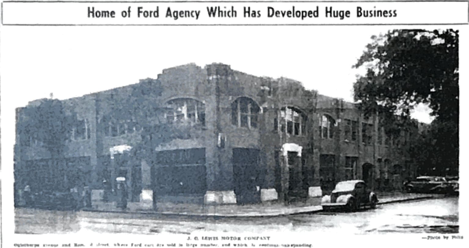 a black and white photo of a building in the middle of a street with cars parked in front of it