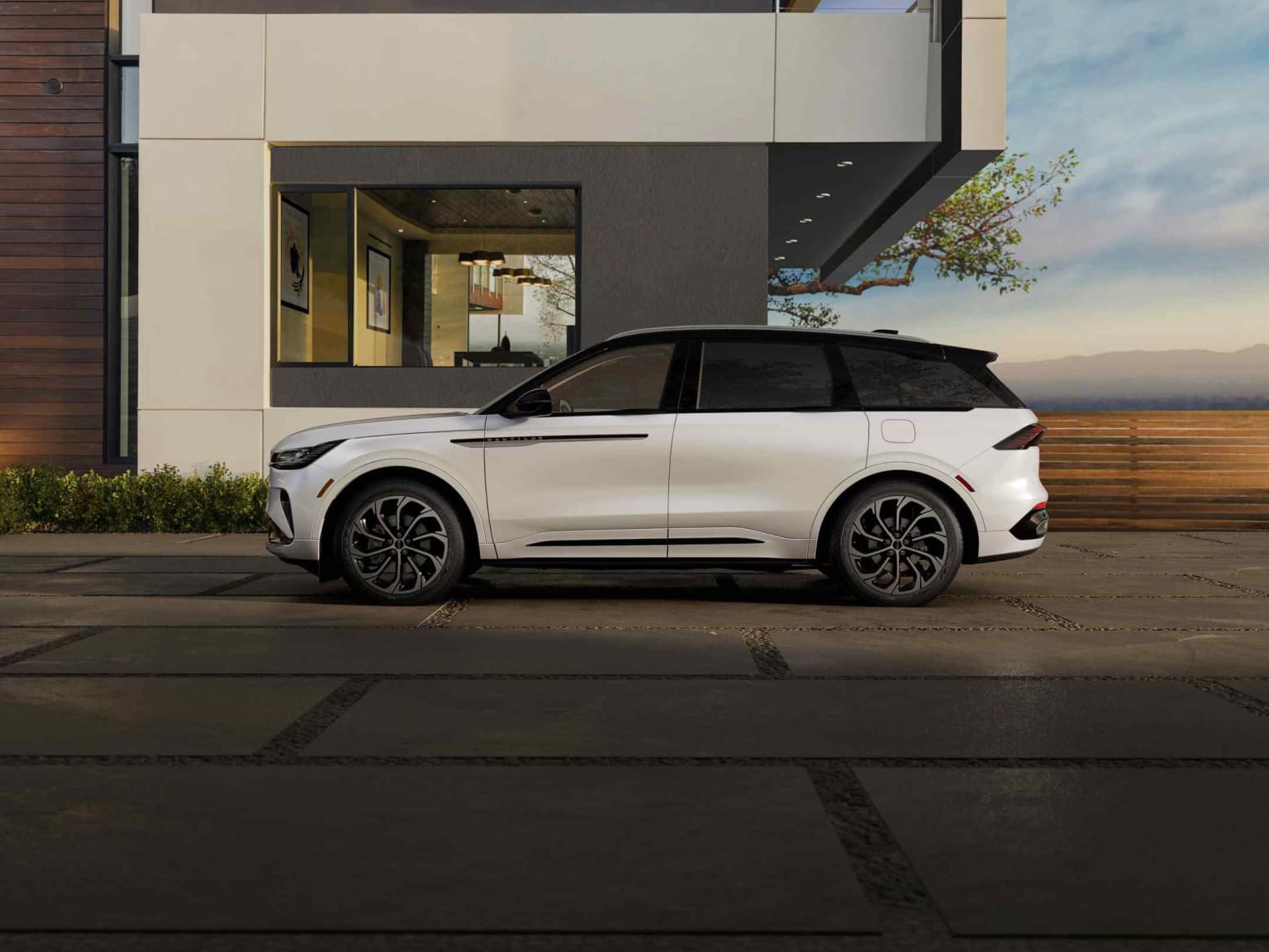 A white SUV in front of a modern building with a glass facade, surrounded by greenery.