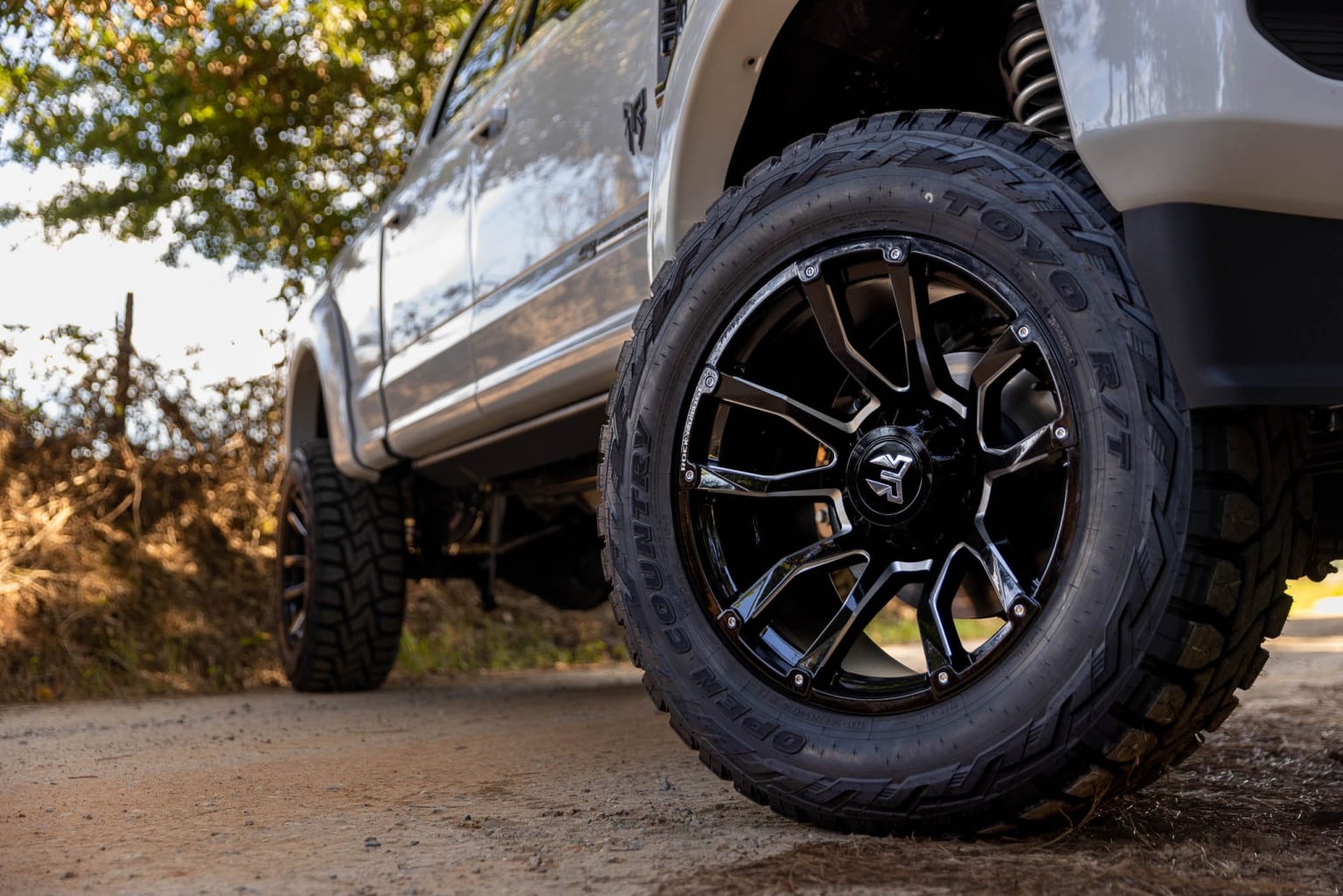 Off-road vehicle with large, knobby tires on a dirt road surrounded by greenery