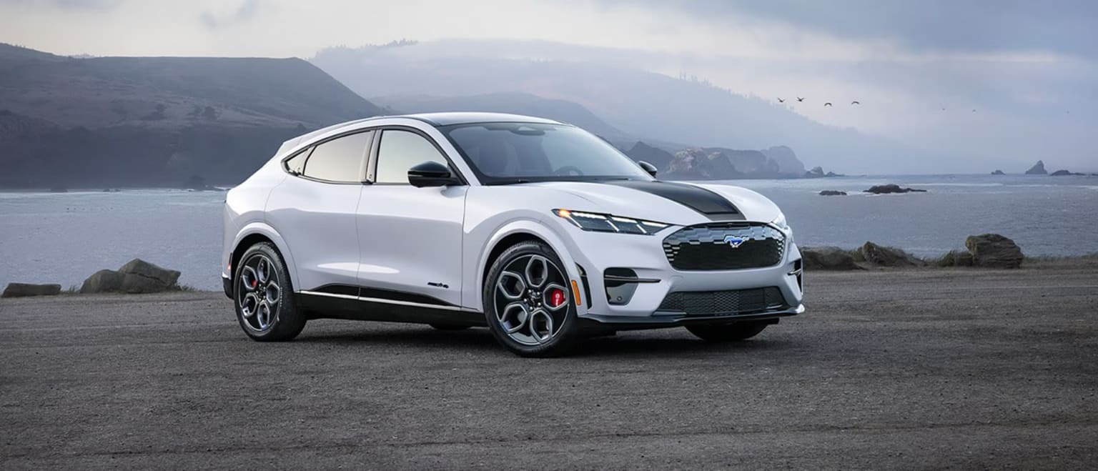 Electric SUV on a rocky beach with mountainous landscape in the background