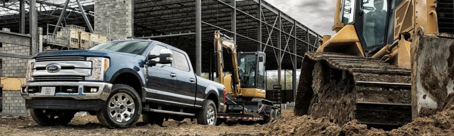 A large pickup truck parked with a construction site and industrial building in the background.