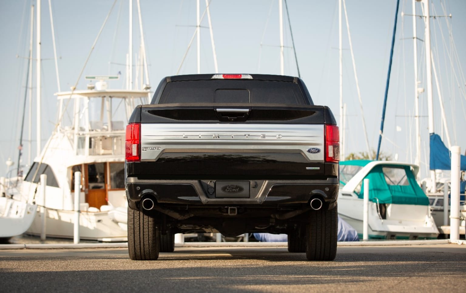 a truck is parked in front of a bunch of boats in the harbor of a harbor with boats in the background