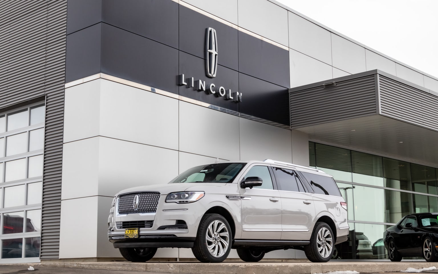 a white suv is parked in front of a lincoln dealership in a parking lot in front of a building