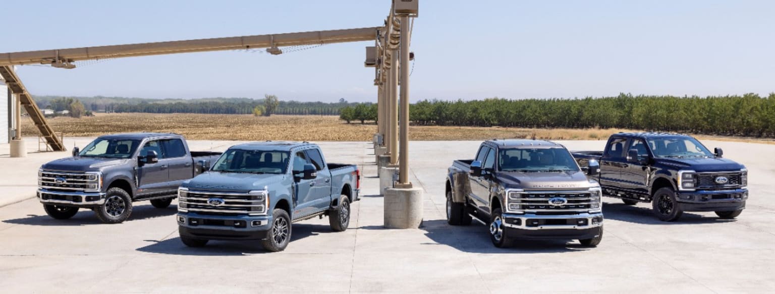 four trucks parked in a parking lot next to a tall pole with a sign on it's side