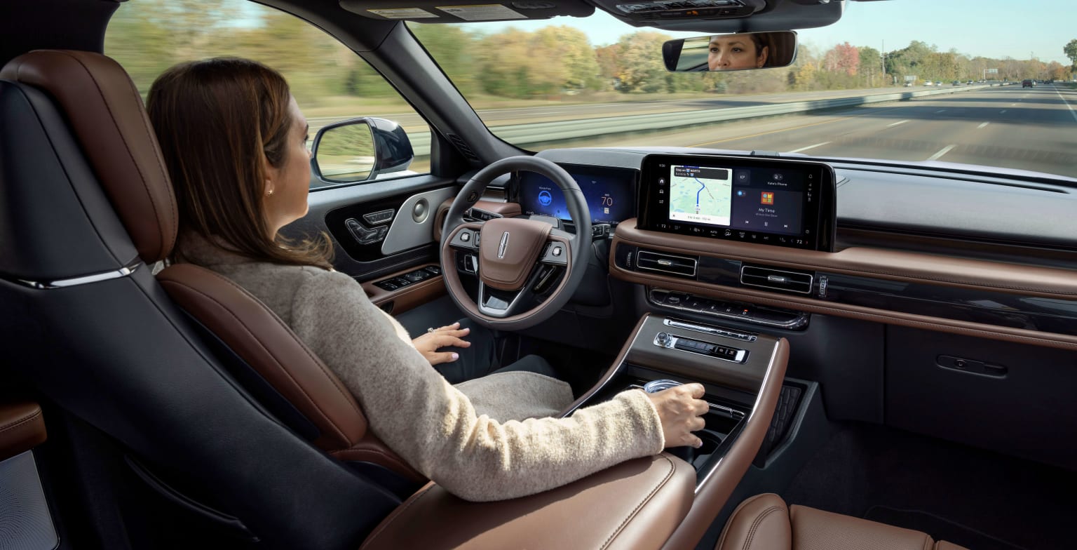 a woman driving a car on a highway with a view of the road from the driver's seat