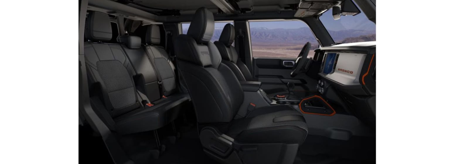"Interior of a large vehicle with multiple rows of black leather seats and various controls and displays visible throughout the cabin."