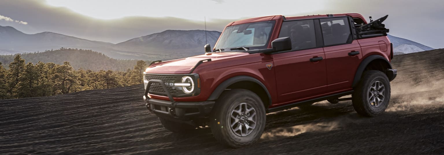 An off-road vehicle parked on a dirt road in a mountainous area.