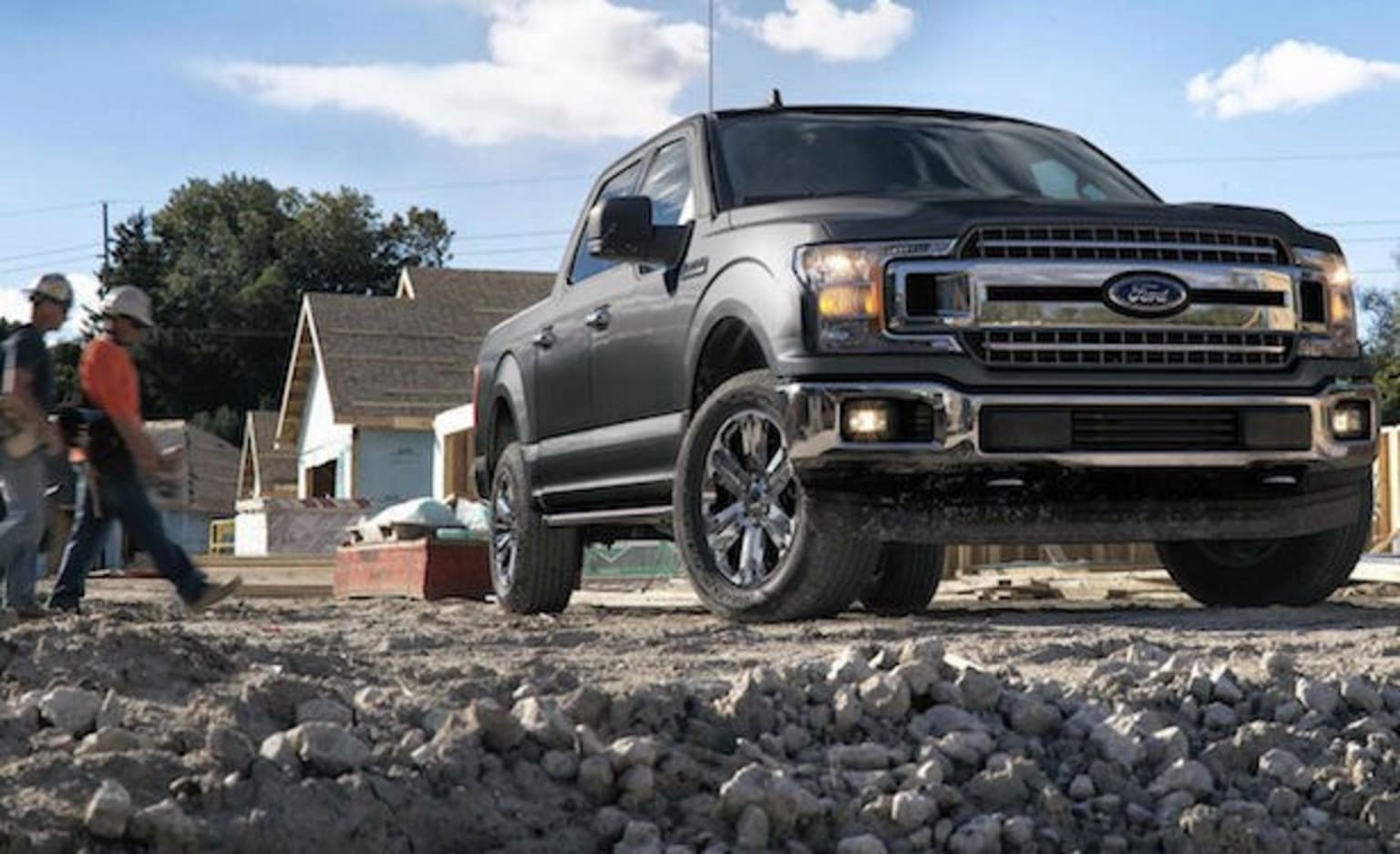 a black truck parked on top of a pile of rocks next to a man in a red shirt and jeans