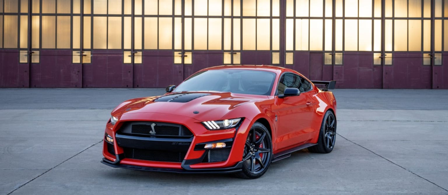 a red sports car is parked in front of a building with a large glass window in the front of it