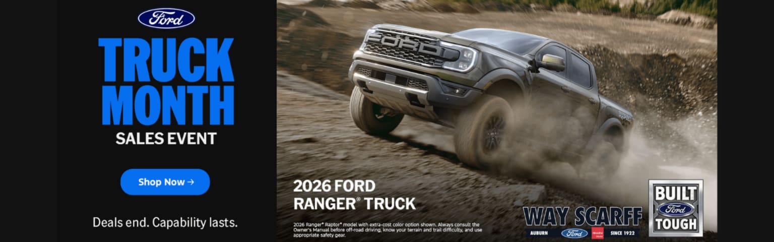 An off-road truck is speeding through a dusty terrain, kicking up a cloud of dirt behind it.