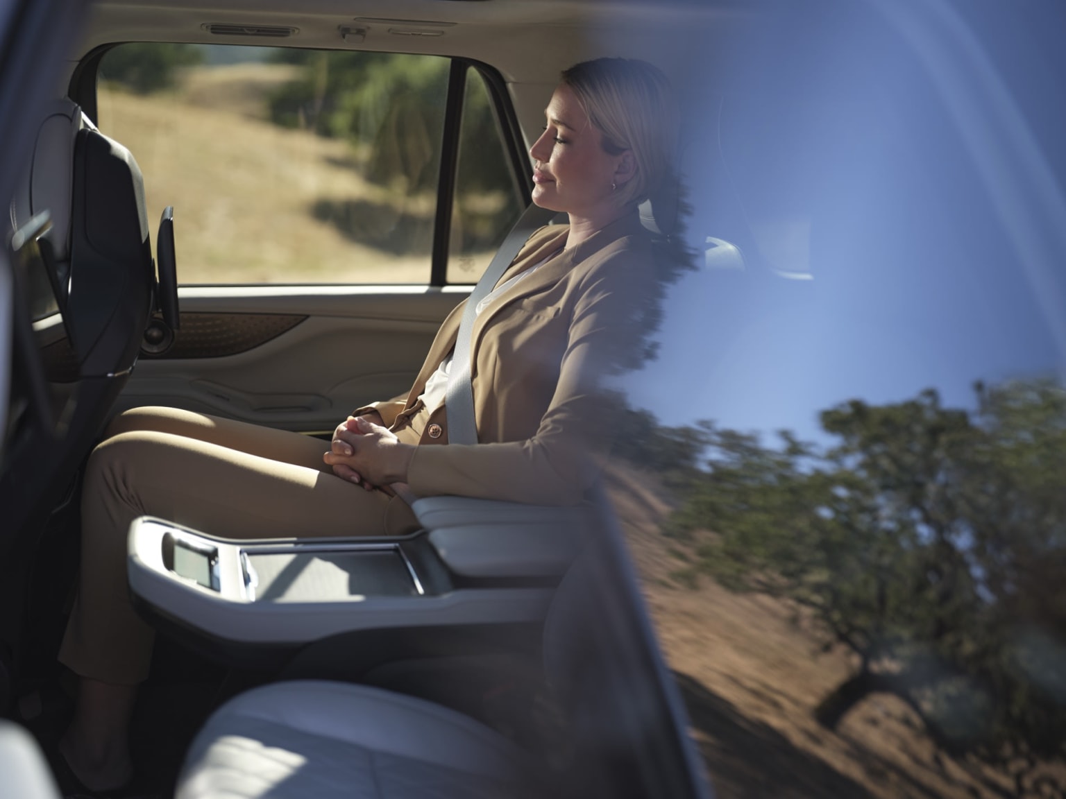 View from the outside looking through the rear window into the 2026 Lincoln Navigator interior of a woman comfortably sitting in the middle row